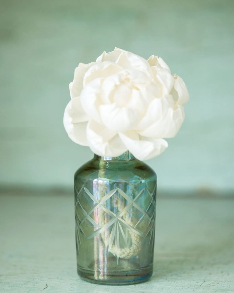 Green glass diffuser bottle with white handmade diffuser flower