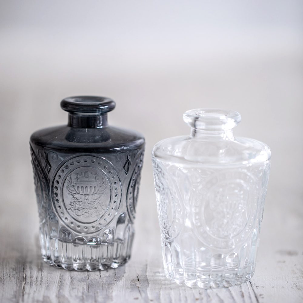Clear and smoked black vintage-style patterned diffuser bottles side by side