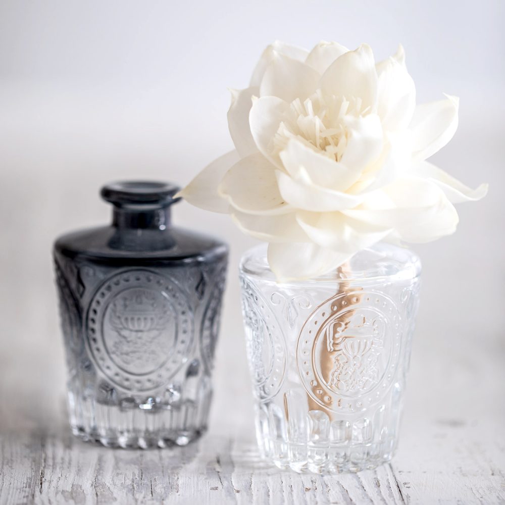 Clear and smoked black vintage-style patterned diffuser bottles with white diffuser flower