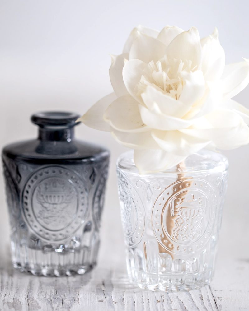Clear and smoked black vintage-style patterned diffuser bottles with white diffuser flower